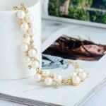Un bracelet de perles et doré sur une tasse blanche
