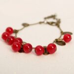 Bracelet vintage femme avec pendentif cerise rouge. Bonne qualité et très originale.