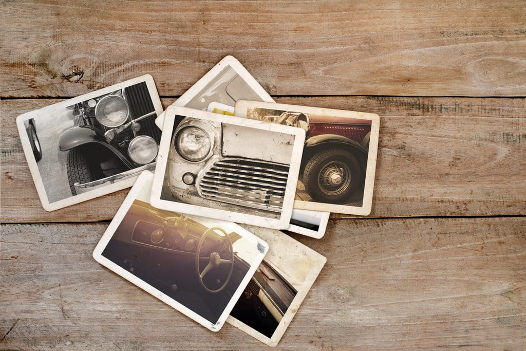 sur un fond en bois, sont posées des photos vintage de voiture en plans rapprochés.