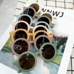 plusieurs paires de lunettes de soleil pour enfant colorées sur un présentoir