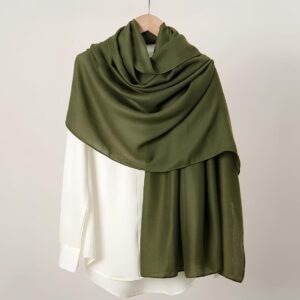 Écharpe voile long en lin de couleur verte sur une chemise blanche sur un cintre.