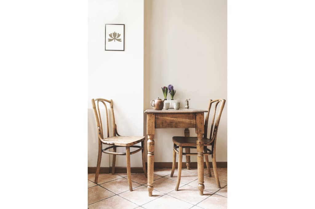 une petite table en bois ainsi que 2 chaises en bois rétro sont dans une cuisine.