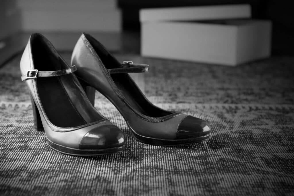 chaussures à bouts ronds à talons posées sur un sol en moquette. la photo est en noir et blanc.