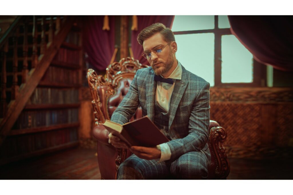 un dandy en costume complet est assis dans une bibliothèque et lit un vieux livre.