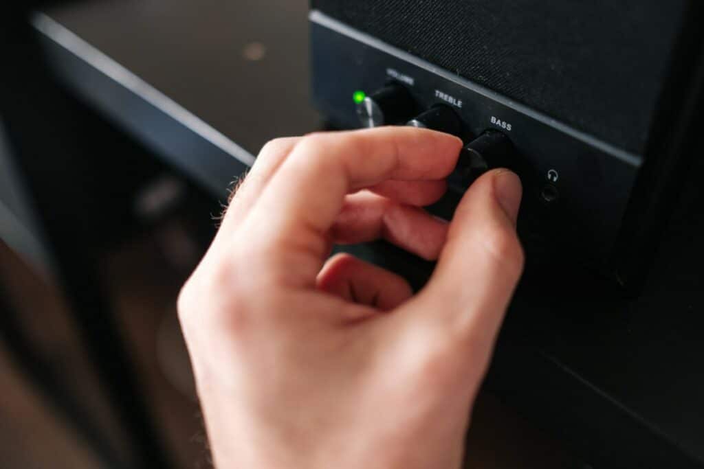 Comment choisir un ampli vintage ? Objets vintage vue zoommée sur une main qui tourne le bouton Bass d'un ampli