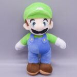 Peluche vintage Luigi, couleurs bleues, marron, vert, blanc qui porte un casquette vert.