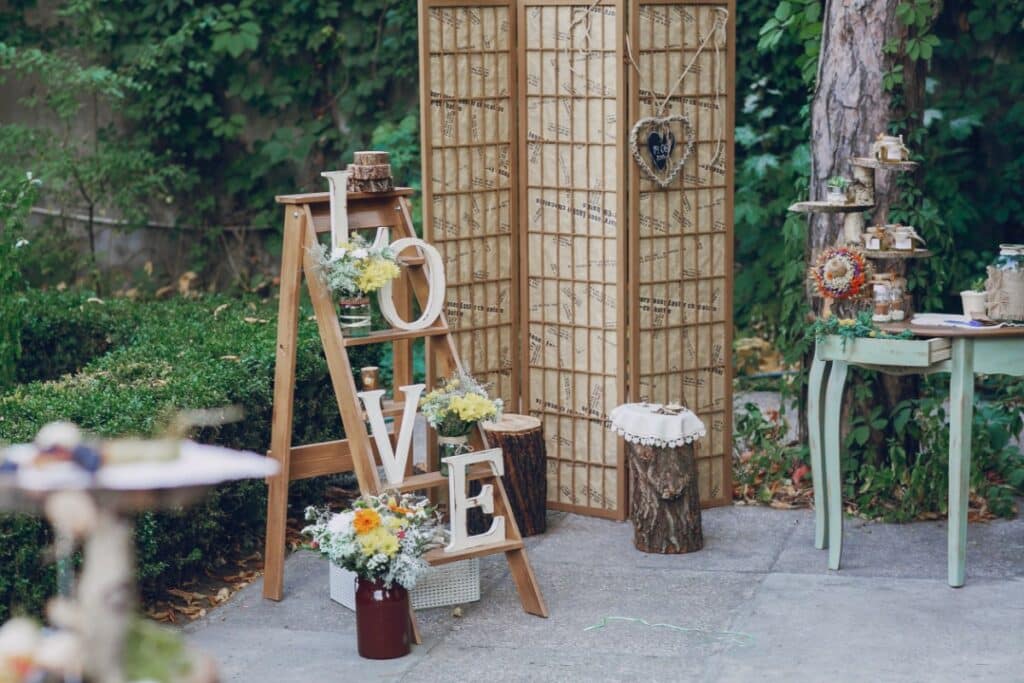 sur une terrasse, des éléments de décoration sont posés dans un coin dédié. sur une échelle en bois décorative sont déposées des lettres L O V E.