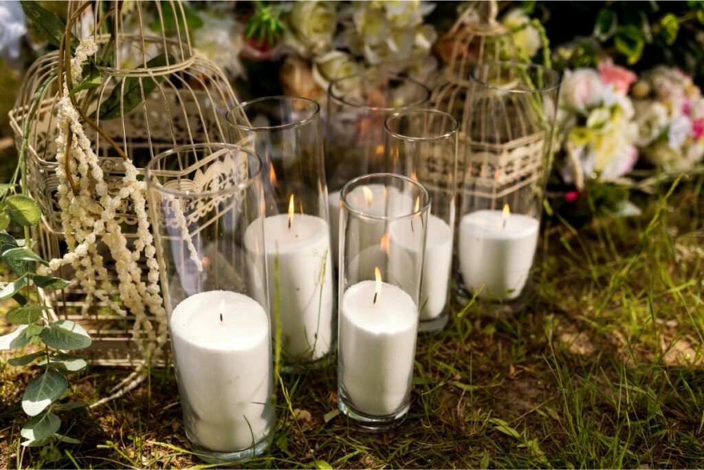 dans l'herbe, vue rapprochée sur des bougies allumées dans des verres, des cages à oiseaux décoratives.