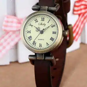 Montre vintage pour femme avec chiffres inscrits à l'ancienne, bracelet en cuir, avec en arrière plan des petits noeuds à carreaux rouge et blanc