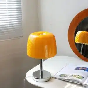 lampe vintage de couleur grise et jaune posé sur un bureau avec un magazine ouvert et devant un miroir
