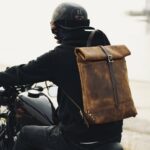 sac de moto vintage en cuir marron porté par un homme conduisant une moto