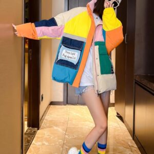 Doudoune vintage multicolore portée par une femme avec un tee-shirt blanc et un short en jean dans un couloir au sol beige et au mur noir