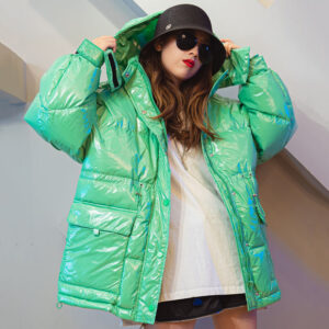 Doudoune vintage de couleur vert pâle portée par une femme au tee-shirt blanc et un chapeau noir avec des lunettes noires devant un mur gris