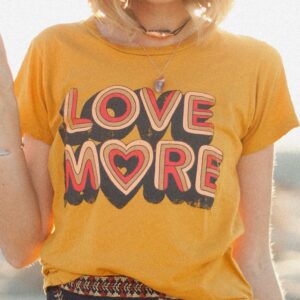 T shirt vintage jaune avec un motif en couleur orange et rouge, porté par une femme avec une jupe noire