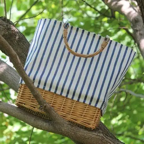 sac en osier tissé et tissé blanc rayé avec anse, présenté dans un arbre
