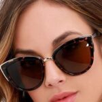 jeune femme qui porte de grosses lunettes marron et noires avec le dessus de la monture dorée