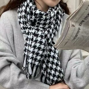 Écharpe femme vintage à motifs noirs portée par une femme avec un haut gris lisant le journal