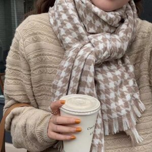 Écharpe femme vintage à motifs beiges portée par une femme avec un haut beige et tenant un gobelet dans la main