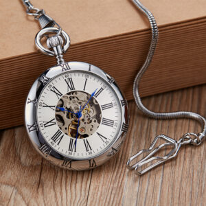 Montre à gousset de couleur argenté à cadran analogique posée sur un petit rebord en bois