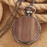 Montre à gousset de couleur argent avec bois, posé sur une corde beige