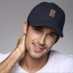 Casquette vintage de couleur bleue avec un logo marron, portée par un homme avec un haut blanc