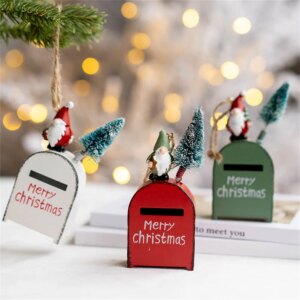 3 petites boîtes aux lettres de couleur blanche, rouge et verte posées dans un décor de Noël avec des lumières en fond