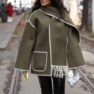 Une femme avec de longs cheveux dans la rue portant une vaste kaki avec des surpiqûres contrastantes blanches.