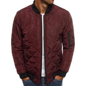 Une veste matelassée style bomber couleur bordeaux portée par un homme avec les mains dans les poches de son jeans.