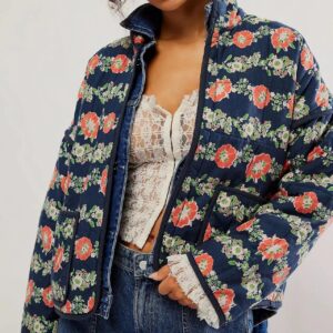 Un femme portant une veste matelassée à fond bleu et motif de fleurs rouge.
