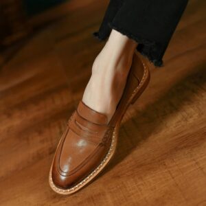 Mocassin à bout rond en cuir porté au pied d'une femme.