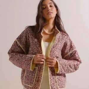 Une femme brune portant une veste courte en motif fleuri rouge.